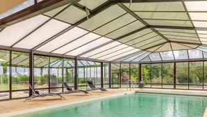 A covered swimming pool with glass walls and lounge chairs. - Architect house with heated pool and secure park (Soulitré)