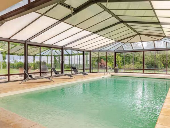 A covered swimming pool with glass walls and lounge chairs. - Architect house with heated pool and secure park (Soulitré)
