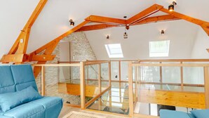 A modern loft bedroom with exposed wooden beams, a stone wall, and a glass ceiling. - Architect house with heated pool and secure park (Soulitré)