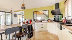 A modern kitchen with a large island, bar stools, and a dining area. - Architect house with heated pool and secure park (Soulitré)