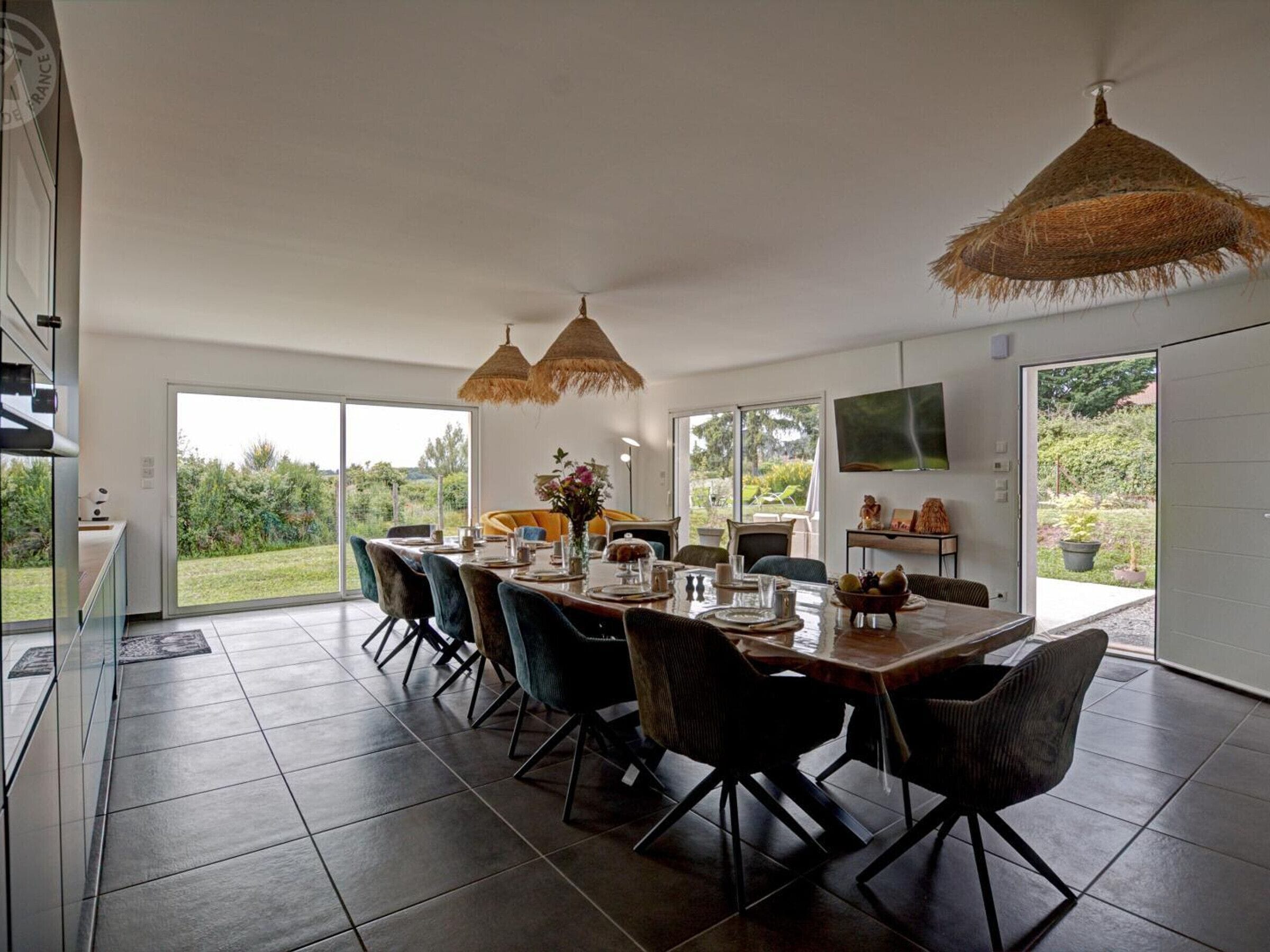 Un comedor moderno con una mesa grande, sillas y vistas al exterior.