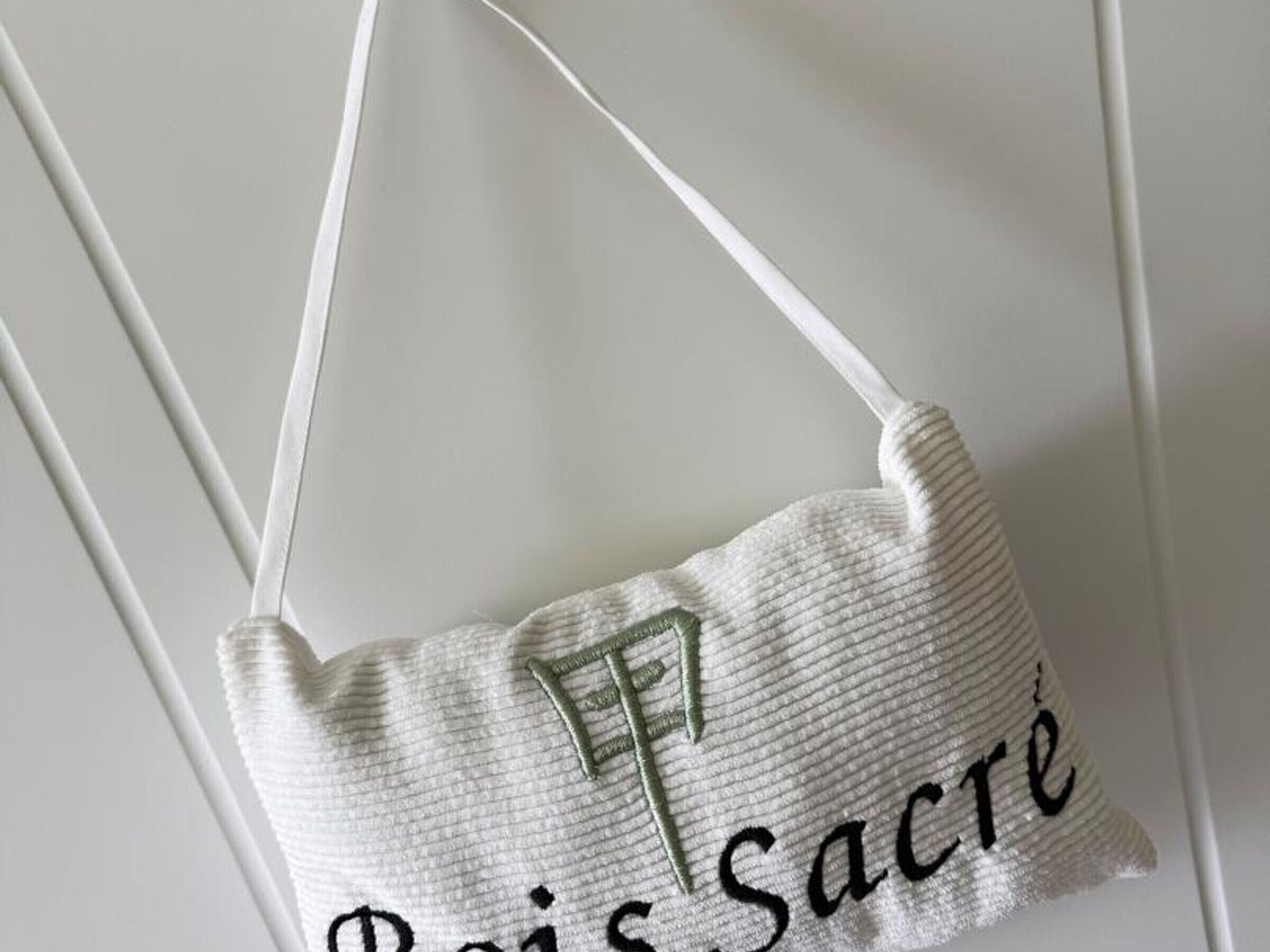 Un oreiller blanc orné d’un texte brodé et d’une lettre « F ».