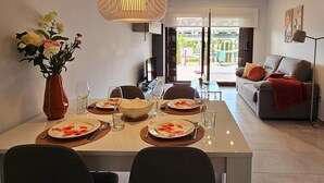 A dining area with a table set for four, a vase with flowers, and a view of the outdoors. - Modern apartment in San Juan de los Terreros with pool and air conditioning (San Juan de los Terreros)