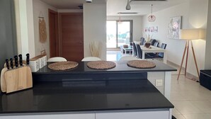 A modern kitchen with a black countertop, a knife block, and a dining area with a table and chairs. - Comfortable Apartment in Pulpí, Andalusia, 2 Bedrooms (Pulpí)