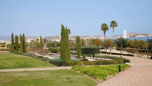 Un jardín ajardinado con senderos, setos bien recortados y árboles altos.