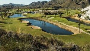 A golf course with a pond, sand bunkers, and a mountainous backdrop. - Charming apartment in San Juan de los Terreros (San Juan de los Terreros)