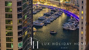 Una marina con diversi yacht ormeggiati, circondata da edifici alti con balconi e finestre illuminate.