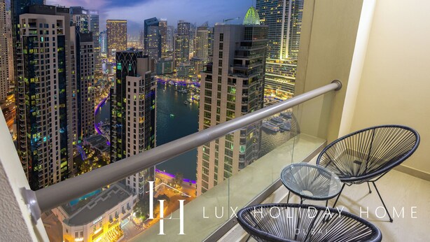 Un balcone con vista sulla città illuminata di notte, con grattacieli e un fiume.