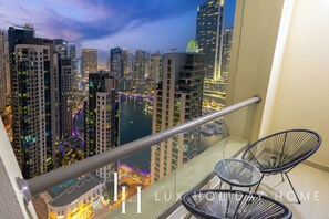 A balcony with a view of a cityscape at night, featuring high-rise buildings and a river. - LUX Contemporary Marina View Suite 7 (Dubai)