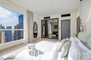 A modern hotel room with a large bed, a city view, a sliding door closet, and a large mirror. - LUX Contemporary Marina View Suite 7 (Dubai)