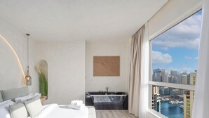 Camera d'albergo moderna con un'ampia finestra, un letto, una scrivania, una vasca da bagno e vista sulla città.