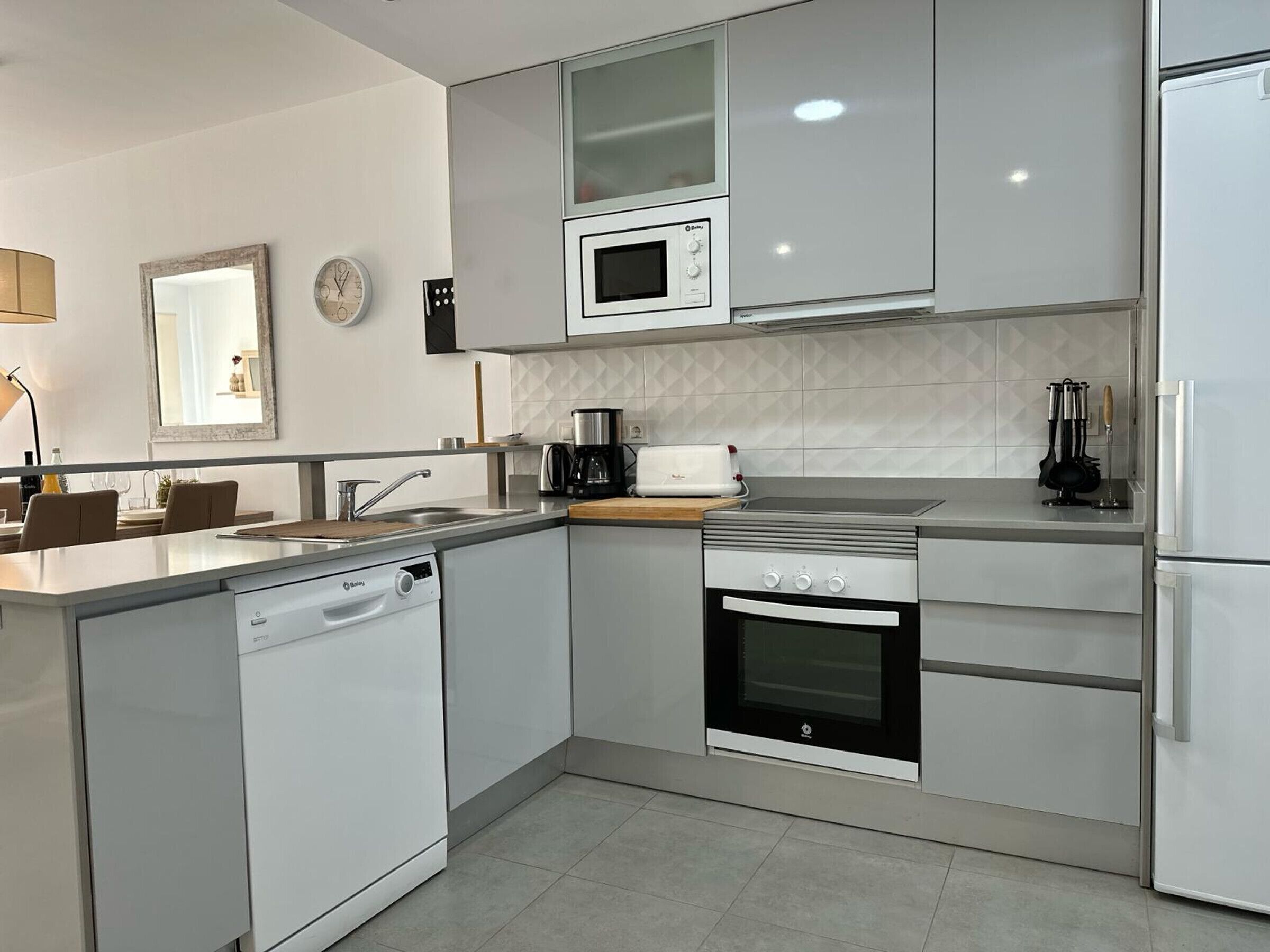 A modern kitchen with white cabinetry, a built-in microwave, a stove, and a dishwasher.