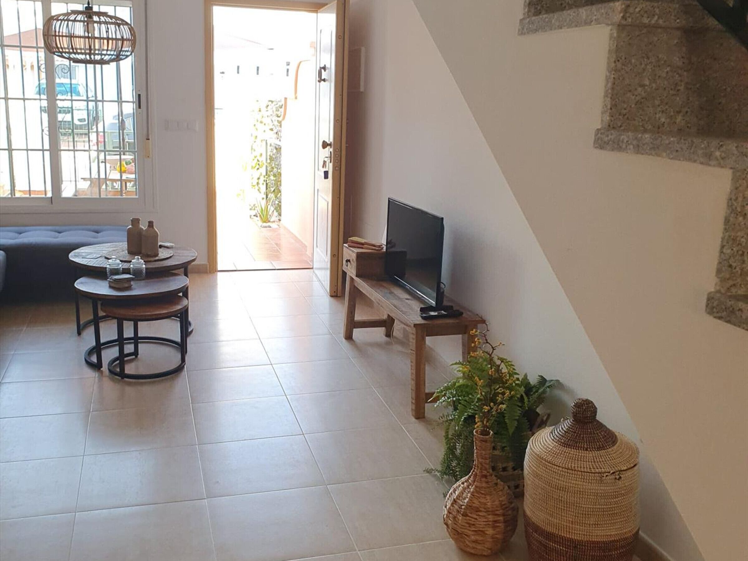 Uma sala de estar com sofá, mesa redonda, televisão em um móvel e cestos de vime.