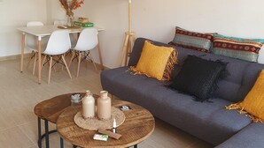 Ett modernt vardagsrum med en grå soffa, ett träbord och en matplats med vita stolar och ett vitt bord.