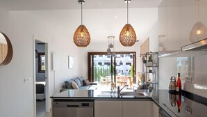 Una cocina moderna con una isla central, electrodomésticos de acero inoxidable e iluminación colgante.