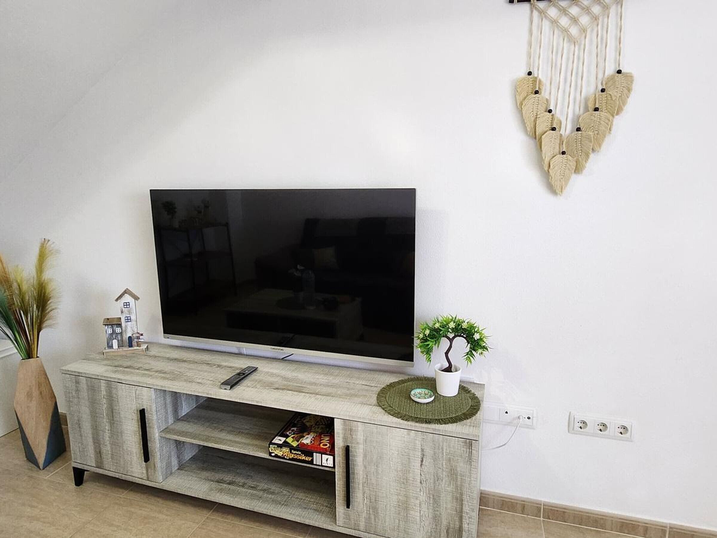 Olohuoneessa on litteänäyttöinen televisio, joka on sijoitettu puiseen TV-telineeseen. Lisäksi siellä on pieni, taloa muistuttava koriste-esine ja seinällä roikkuu sydämenmuotoinen makramee-seinävaate.