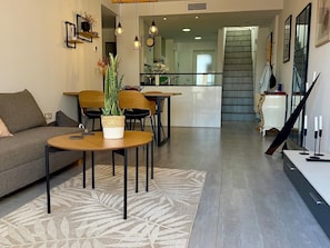 A modern living room with a sofa, a round table, and a potted plant. - Charming apartment 200m from beach with communal garden (San Juan de los Terreros)