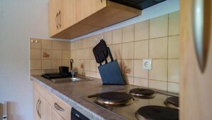 A kitchen with wooden cabinets, a countertop, a sink, and a stove. - Old schoolyard - Apartment Pausenhof (Oberstaufen)