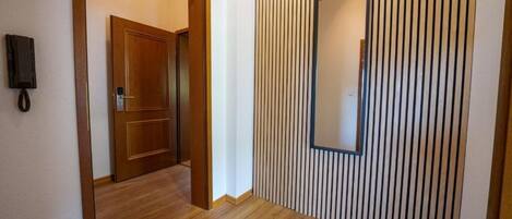 A hallway with wooden flooring and a vertical striped wall.