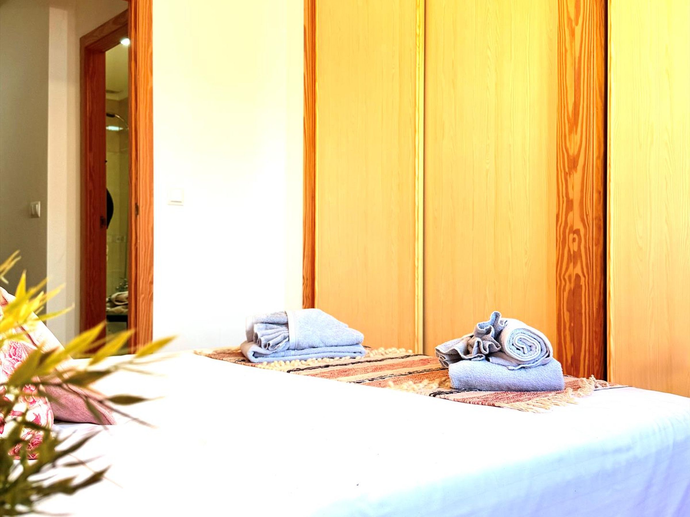 Een kamer met een bed, een houten kledingkast, en een badkamer die door een open deur zichtbaar is.
