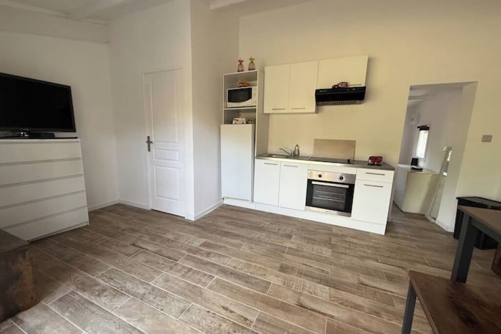 Een kleine keuken met witte kastjes, een magnetron en een fornuis.
