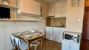 Une cuisine compacte comprenant une table à manger, des chaises, un réfrigérateur et un four à micro-ondes.