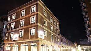 A multi-story hotel with a brick facade, multiple balconies, and illuminated signage. - DİASOS OTEL (İzmir)