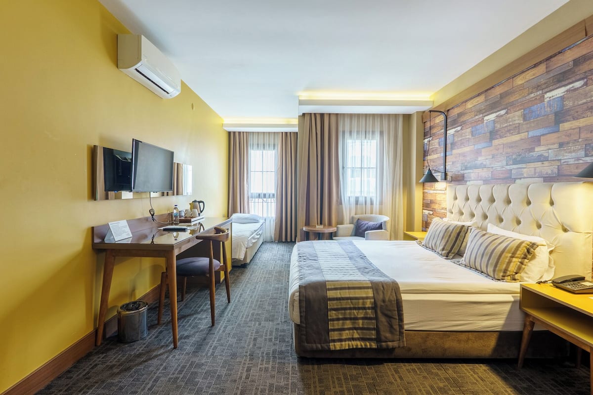Una habitación de hotel con cama, escritorio, silla y televisor.