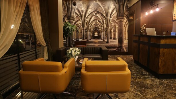 Un vestíbulo con un mural de estilo medieval, una recepción y asientos de cuero.