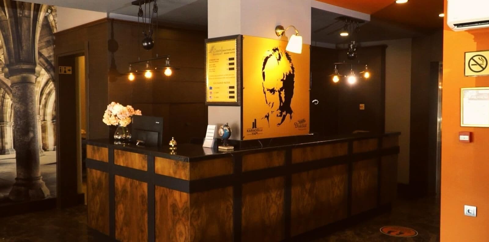 A reception desk with a wooden finish, a large poster of a person, and a menu board.