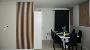 Ett kompakt matområde med ett vitt bord, svarta stolar och en liten krukväxt.
