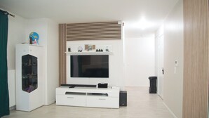 Ett modernt vardagsrum med en platt-TV, en vit TV-bänk och ett litet skåp.