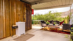 Un patio techado con pared de madera rústica, un lavamanos y mobiliario exterior.
