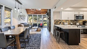 A modern kitchen with a large island, built-in appliances, and a dining area with a wooden table and chairs. - Prime Location: Modern Mountain Charm, Hot Tub, Sleeps 10, Close to Skiing & Dining! (Park City)