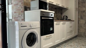 Una cucina compatta con lavatrice, forno a microonde, forno e macchina del caffè sul piano di lavoro.