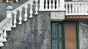 Un edificio in pietra con una porta di legno, una cornice verde e una balaustra bianca.