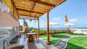 Un espacio exterior techado con cocina, comedor y vista al océano.