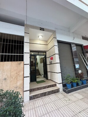 A building entrance with a number 25 sign, a staircase leading inside, and potted plants on the ground. - 2-bedroom apartment in front of Tangier Stadium nearest stadium residence (Tanger)