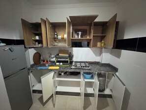 A compact kitchen with a refrigerator, a sink, a gas stove, and open cabinets. - 2-bedroom apartment in front of Tangier Stadium nearest stadium residence (Tanger)