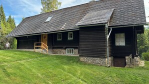Ein Gebäude aus Holz mit geneigtem Dach, einer Holzveranda und einem Steinfundament.