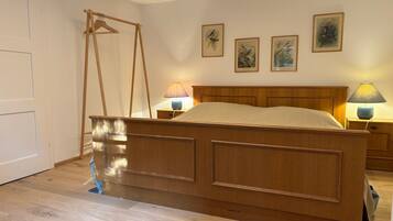 A bedroom with a wooden bed, two bedside lamps, a wooden wardrobe, and three framed wall art pieces.