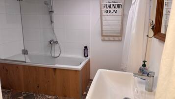 A bathroom with a bathtub, a shower, a sink, and a 'Laundry Room' sign.