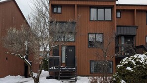 A modern multi-story building with a wooden facade, numbered doors, and a staircase leading to the entrance. - Unit 33 - 4 bedrooms - 10 people (Beaupré)