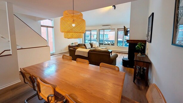 A spacious dining area with a wooden table and wicker chairs, a sofa in the background, and a large window providing natural light. - Unit 33 - 4 bedrooms - 10 people (Beaupré)