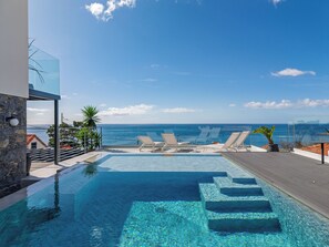 A pool with clear blue water, surrounded by lounge chairs and a view of the ocean. - Villa Lázaro Luxe by HRM (Funchal)