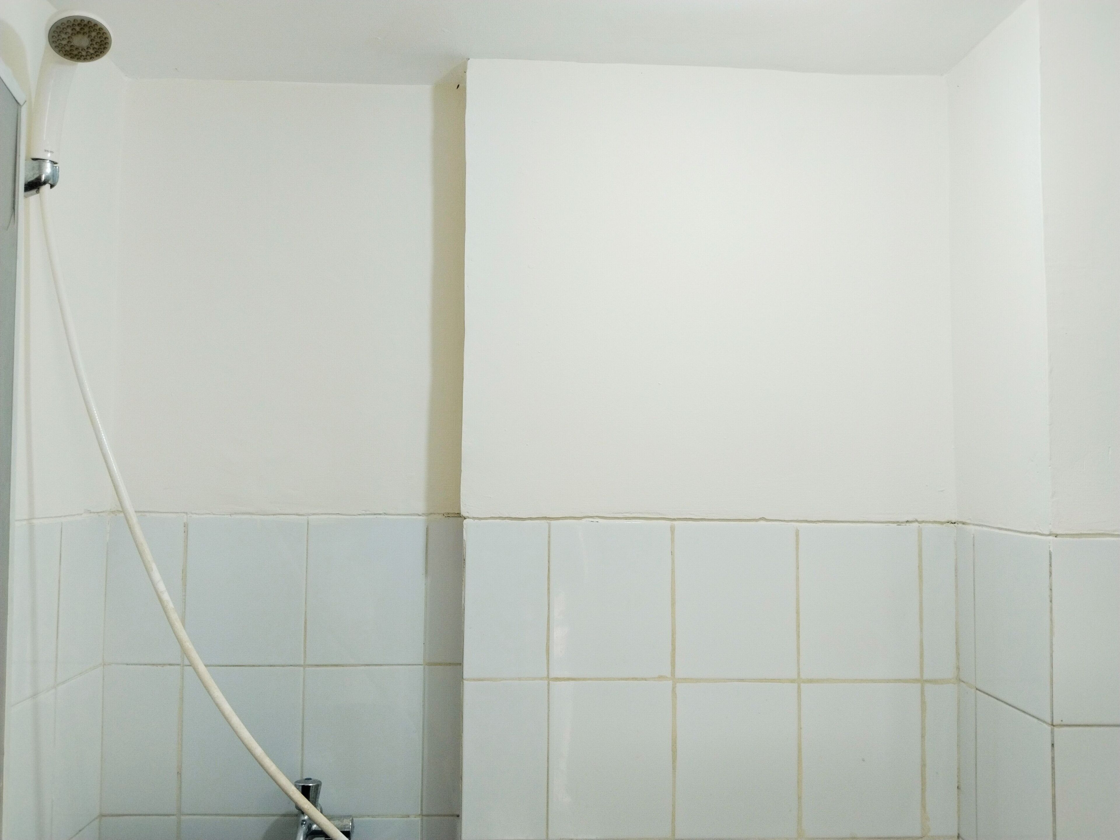 Baño con paredes de azulejos blancos y zona de ducha.