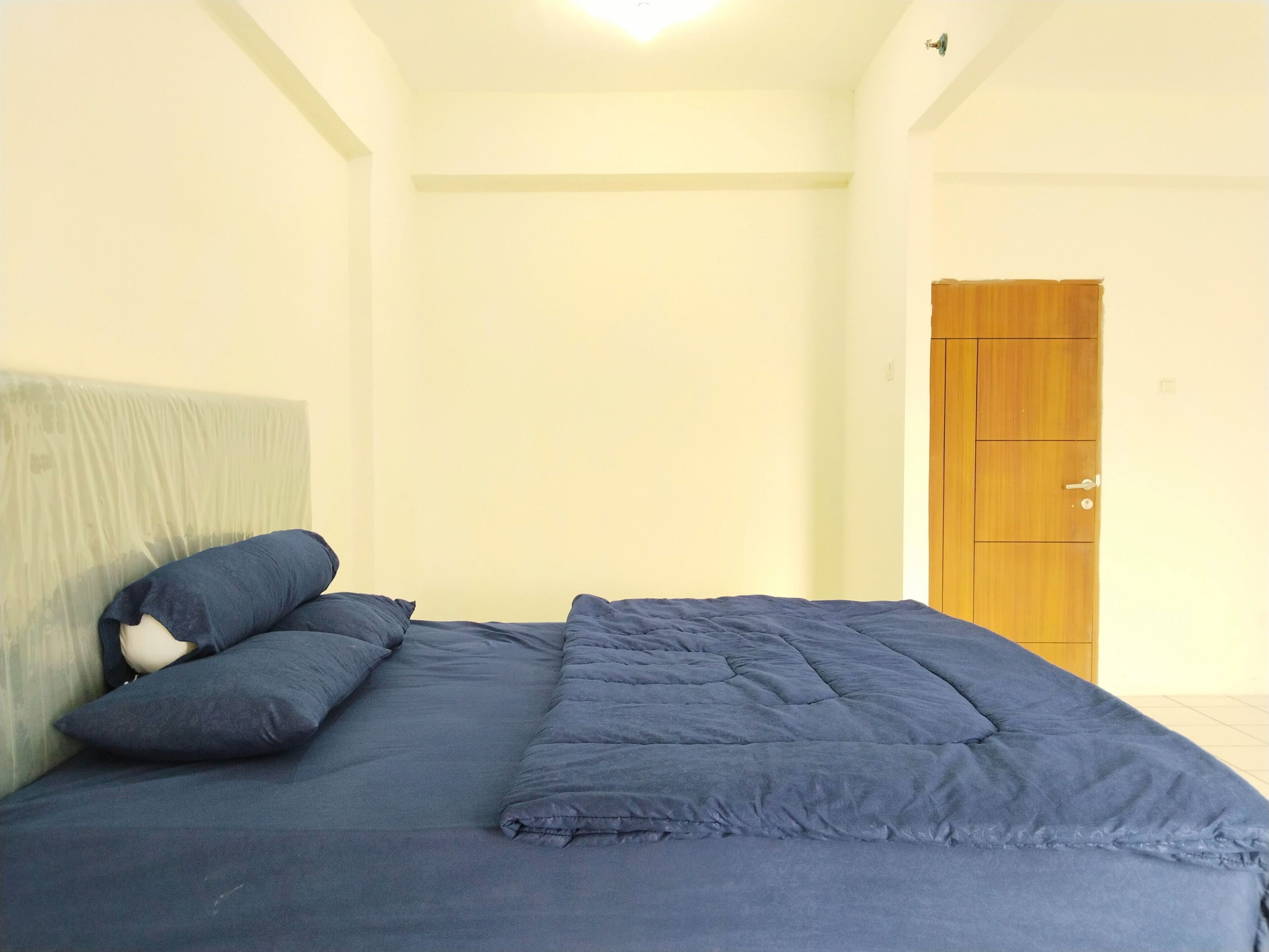 A bedroom with a bed, a wooden wardrobe, and a door.