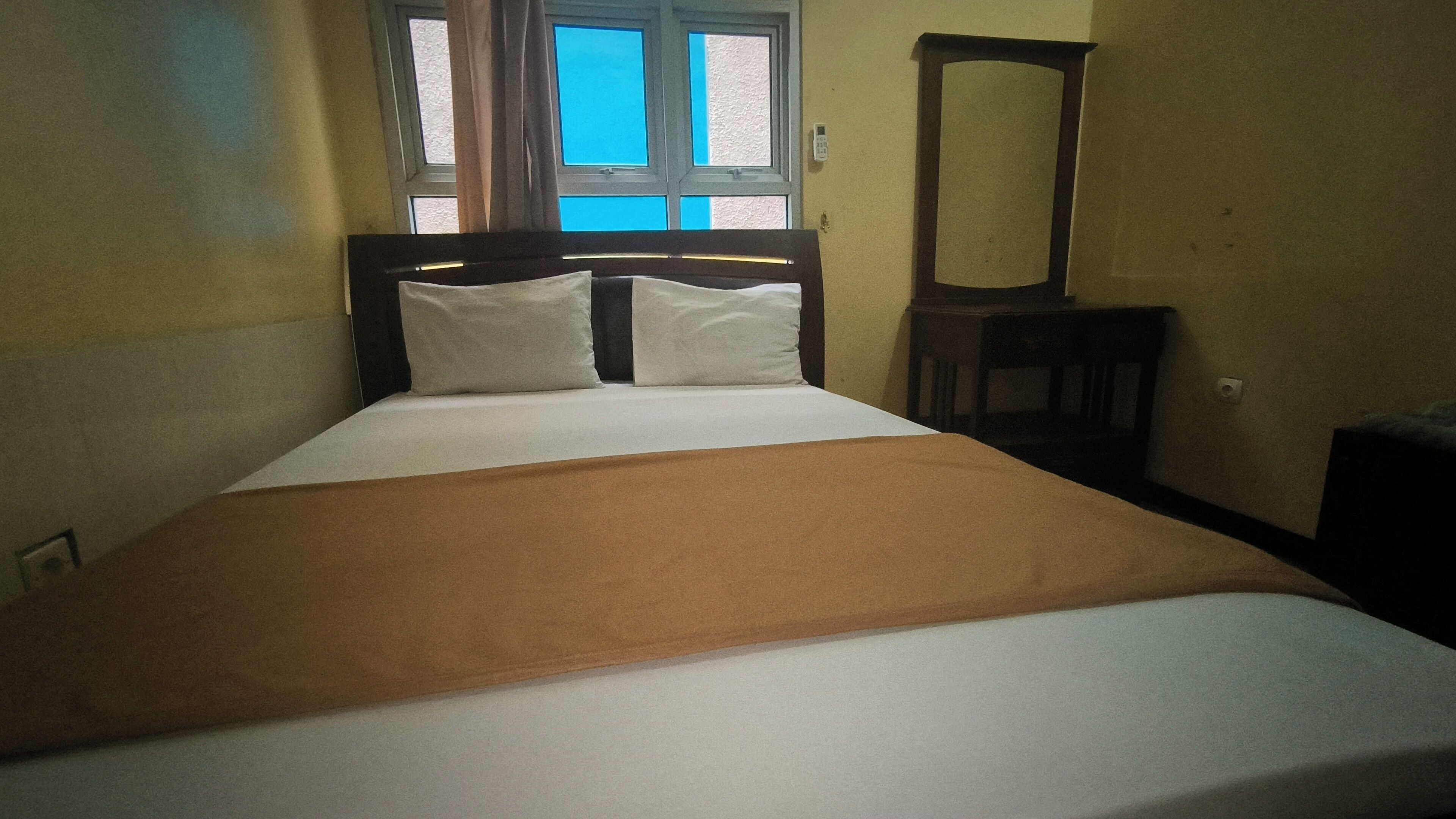 A neatly made bed with a brown blanket, a wooden headboard, and two pillows.