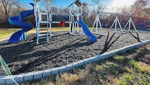 A playground with a blue spiral slide, swings, and a red decoration. - Alto O4 I Modern New Construction 2Bd Apartment (Clarksville)