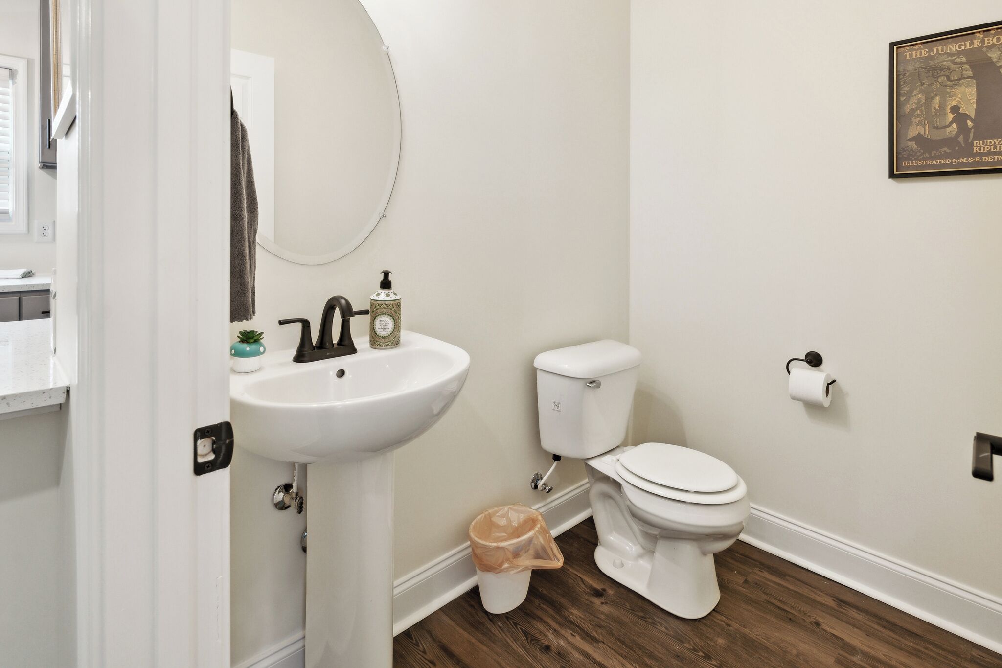 A bathroom with a white sink, toilet, and a trash can.